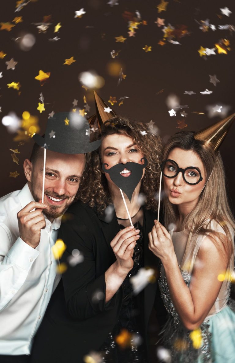 Fotobox-Fun Drei Personen mit Masken und Party-Accessoires, umgeben von Konfetti.