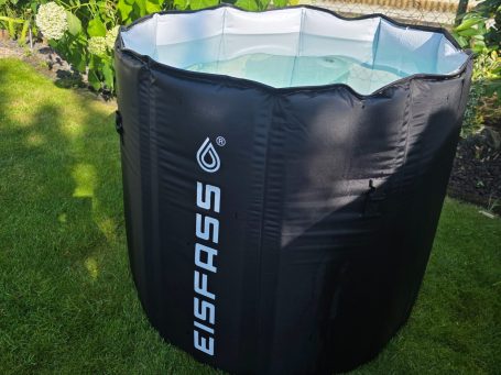 Eisfass mieten Schwarzes, aufblasbares Planschbecken auf grünem Rasen, gefüllt mit klarem Wasser.