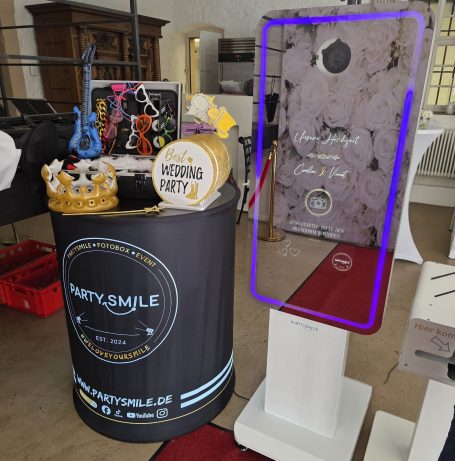 perfekt präsentiert Stand mit Partydeko, inkl. einer Krone, einem Schild und einem Smartphone-Display.