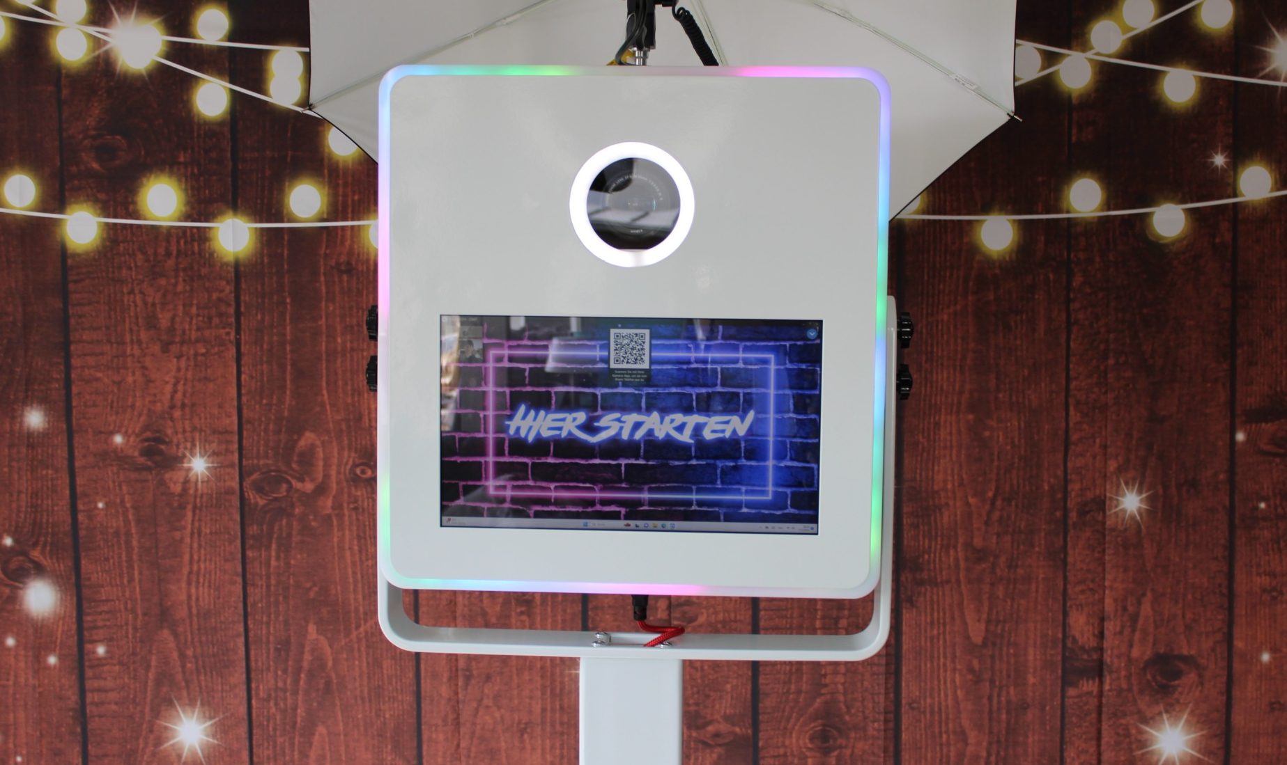 Fotobox Ein fotoautomat mit bunten Lichtern und einem Bildschirm auf Holz-Hintergrund.