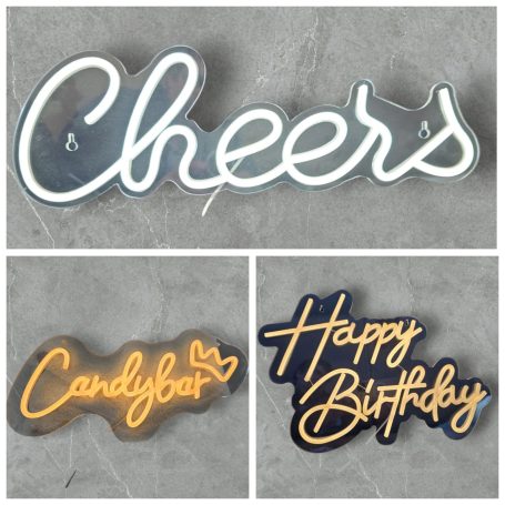 Leuchtschilder Drei Neon-Schilder: "Cheers", "Candybar" und "Happy Birthday" auf grauem Hintergrund.
