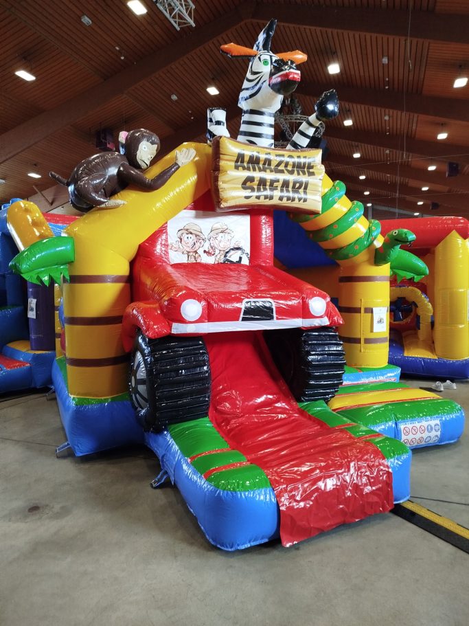 Hüpfburg Buntes Hüpfburg-Auto mit Tieren, Rutsche und Spielbereich in einer Hallenstraße.