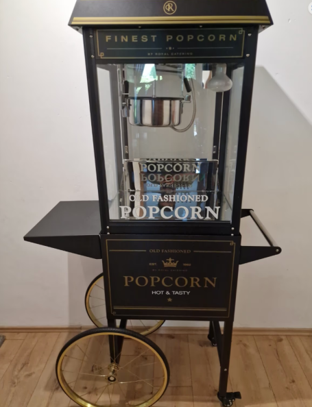 Popcornmaschine Antike Popcornmaschine auf einem Wagen, mit transparentem Gehäuse und goldenen Akzenten.