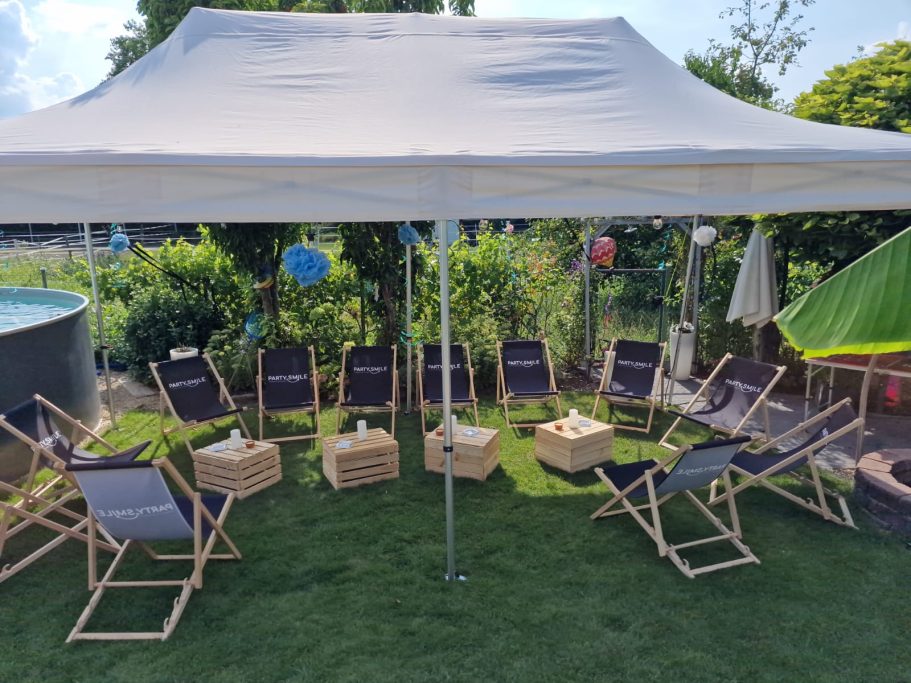 Alles aus einer Hand Sitzbereich unter einem Zelt mit Liegestühlen und Tisch in einem Garten.